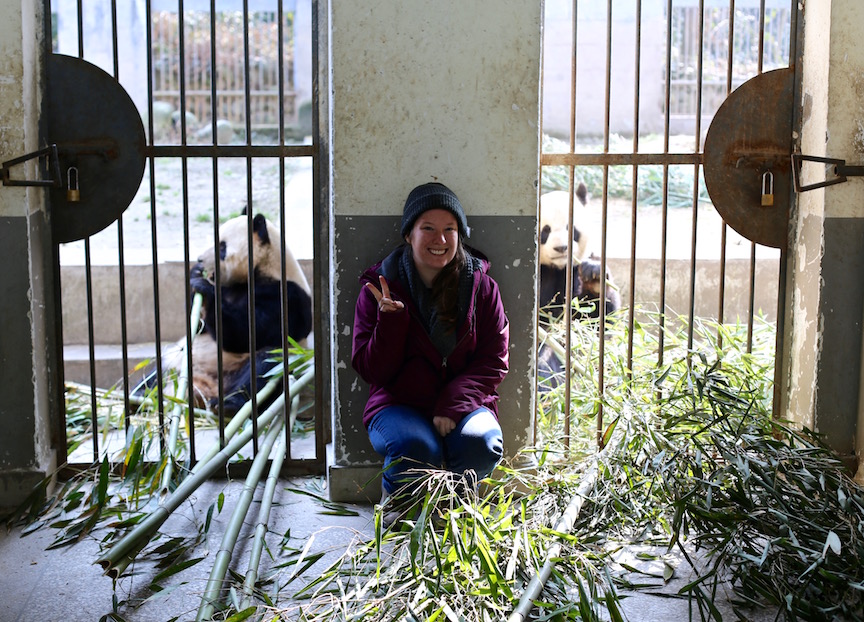 Jenn giving the typical Chinese photo pose next to the pandas.
